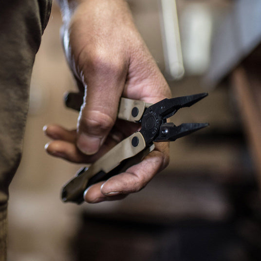 Translation missing: en.Hand holding Coyote Rebar with pliers open with a blurred workshop background
