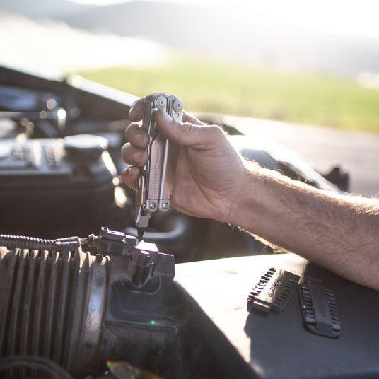 Translation missing: en.Leatherman Surge being used to work on a truck with a bit kit set