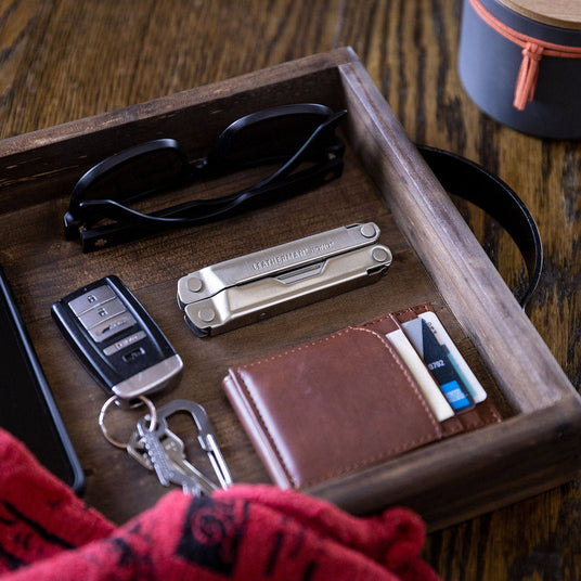 Translation missing: en.A stainless steel Leatherman Bond closed on a tray next to a wallet, keys and sunglasses