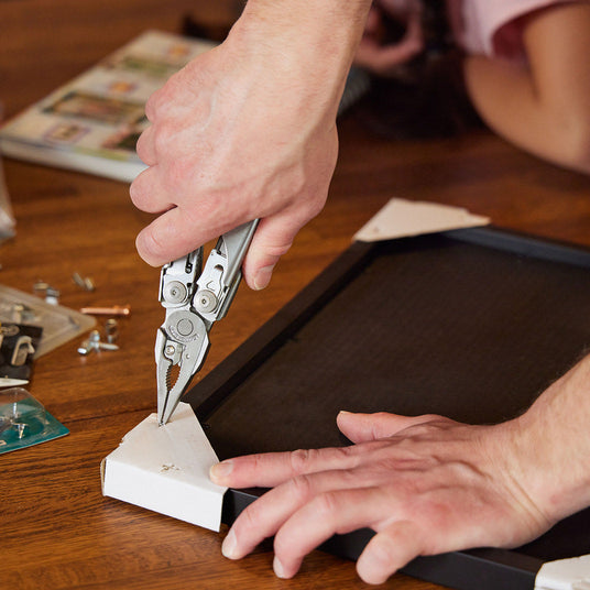 Translation missing: en.Someone using the pliers on a Leatherman Surge to fix a picture frame