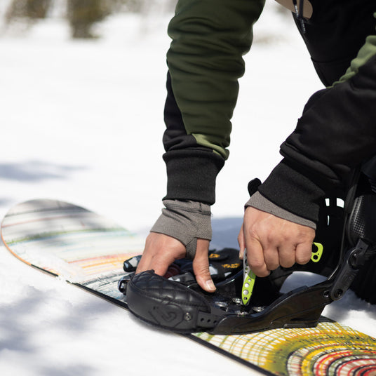 Translation missing: en.Person using Skeletool to secure binding on a snowboard