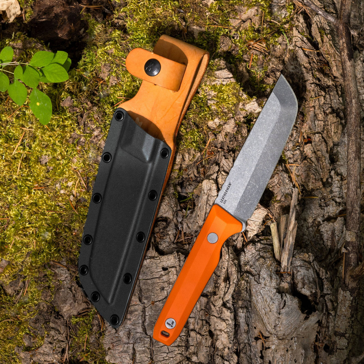 Translation missing: en.Leatherman Pioneer knife alongside a sheath lies on the ground, with natural elements like dirt and grass around them