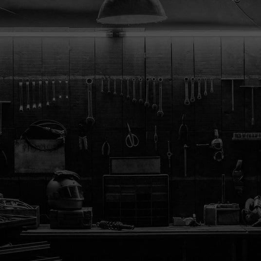 Translation missing: en.A dimly lit workshop with various tools hanging on the wall, a workbench, and storage drawers