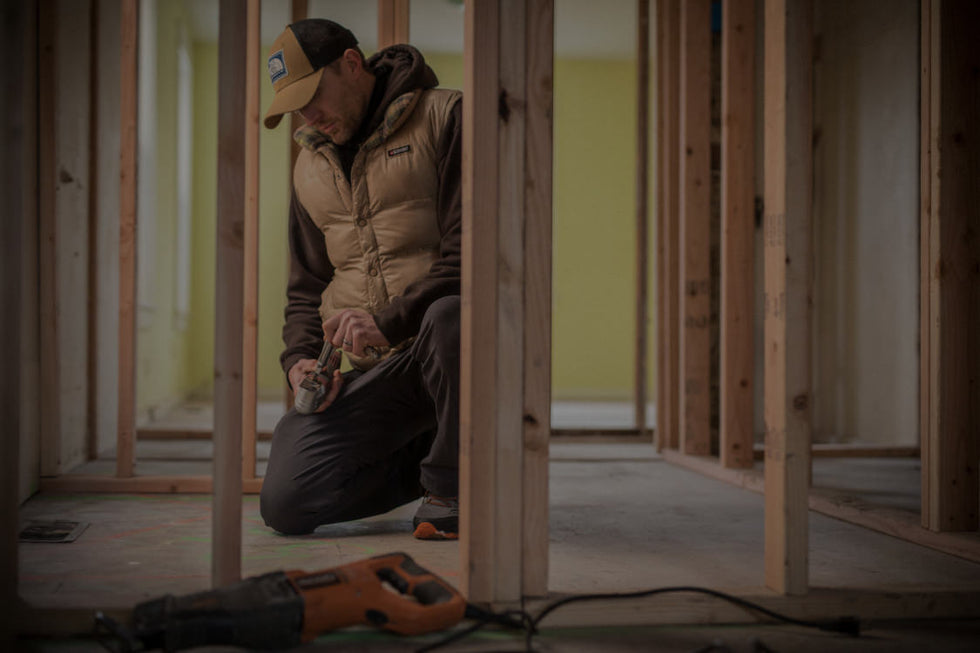 Translation missing: en.A man in a jacket is actively engaged in work at a construction site, surrounded by tools and equipment