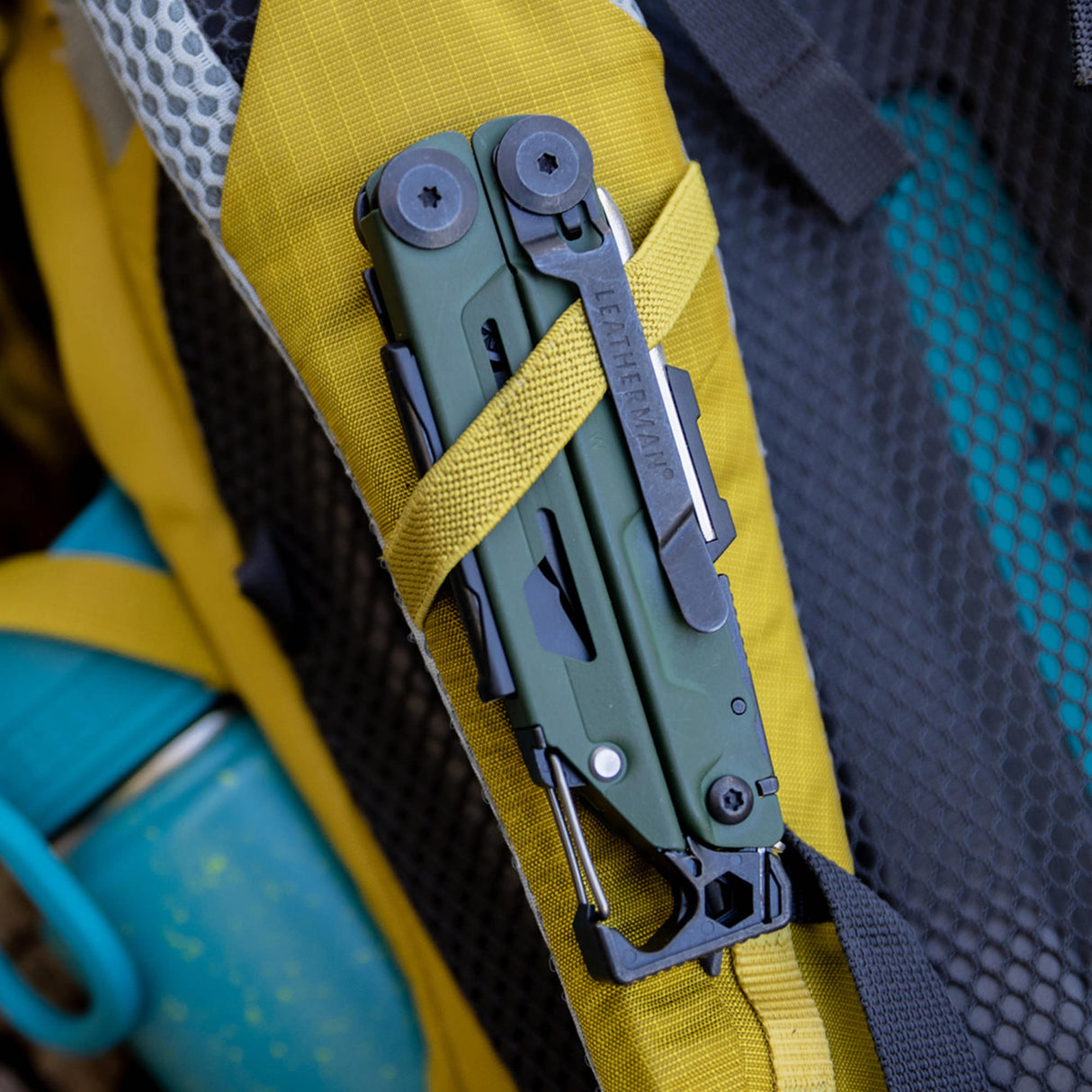 Translation missing: en.Signal green Leatherman multitool clipped to yellow backpack strap with water bottle in side pocket
