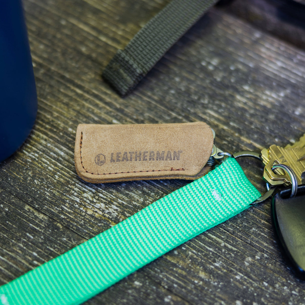 Translation missing: en.Micra sized brown leather tool sleeve protecting the multi tool while attached to a bright green keychain