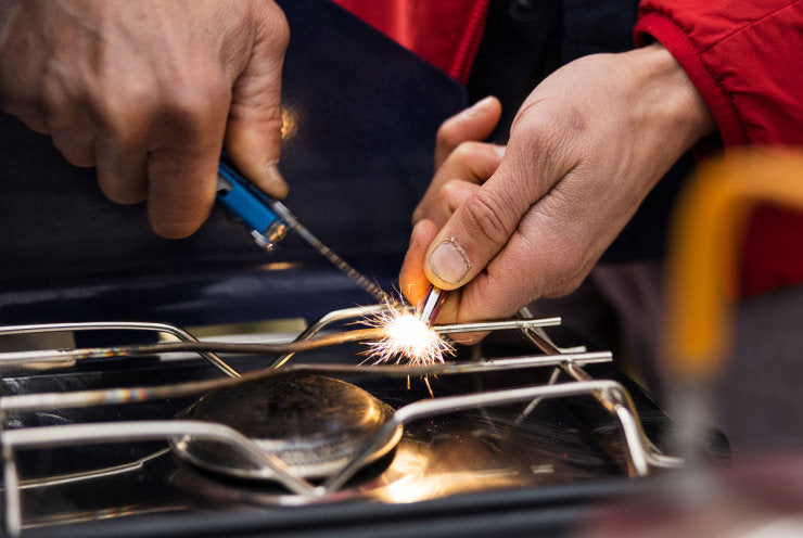 Someone using a Leatherman Signal fire starter to light a camping stove.