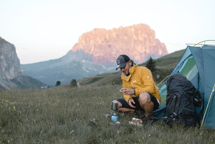 Man camping outdoors, with a camping stove.