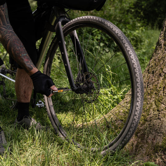 Person repairing a bicycle’s front wheel outdoors using Leatherman Signal