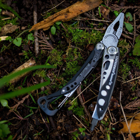 Skeletool CX open laying on forest ground that is covered in moss and twigs