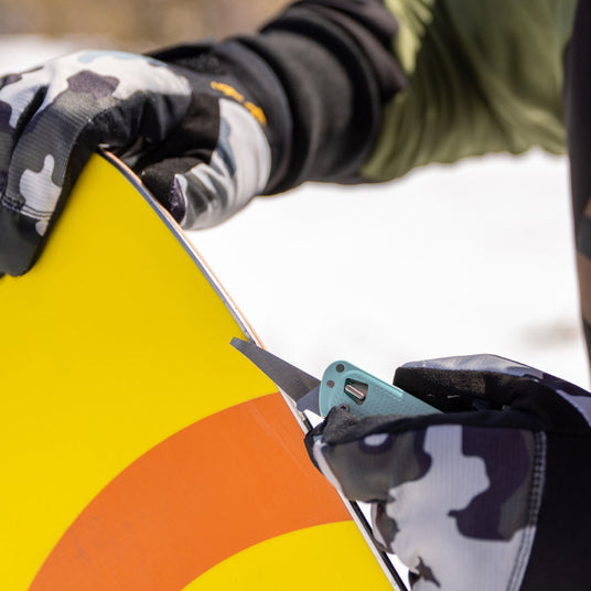 Person sharpen the edge of a snowboard with a Leatherman FREE T4.