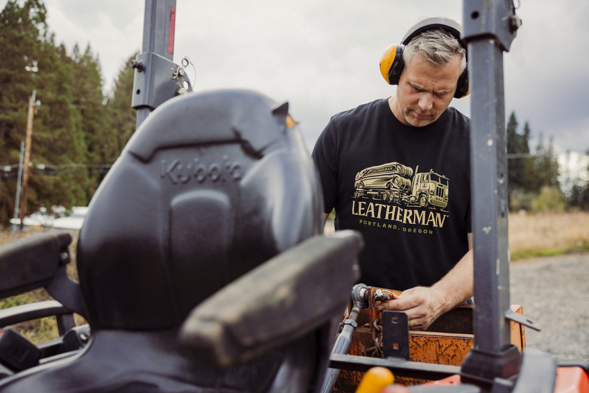 Translation missing: en.A person wearing a black Leatherman Timber Tee working on a tractor outdoors