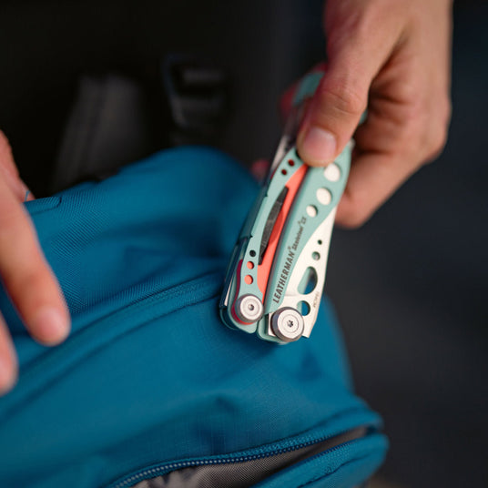 Person holding closed Skeletool CX over a backpack