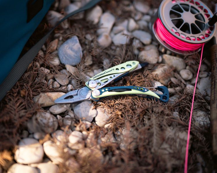 Skeletool CX open showing pliers on the ground outside next to a fishing line