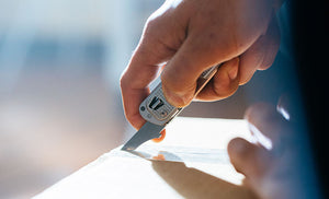 Translation missing: en.Man using box opener on Leatherman T2 to open brown box
