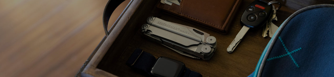 Leatherman Wave+ next to Apple watch, brown leather wallet and keys in wooden box.