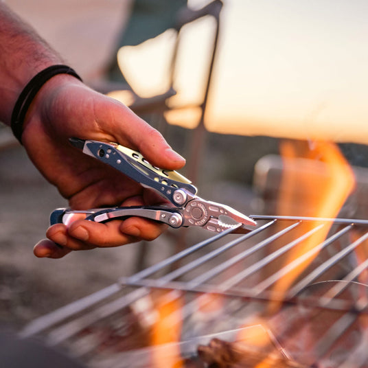 Man using Skeletool CX pliers to move a hot grill rack