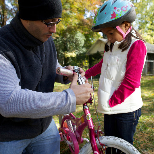 Dad using a Leatherman Wave to attach a bell to daughters bike