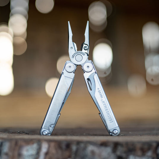 Leatherman Wave open with pliers showing standing upright on a log