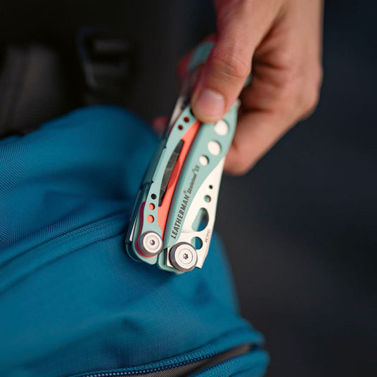 Person holding closed Skeletool CX over a backpack