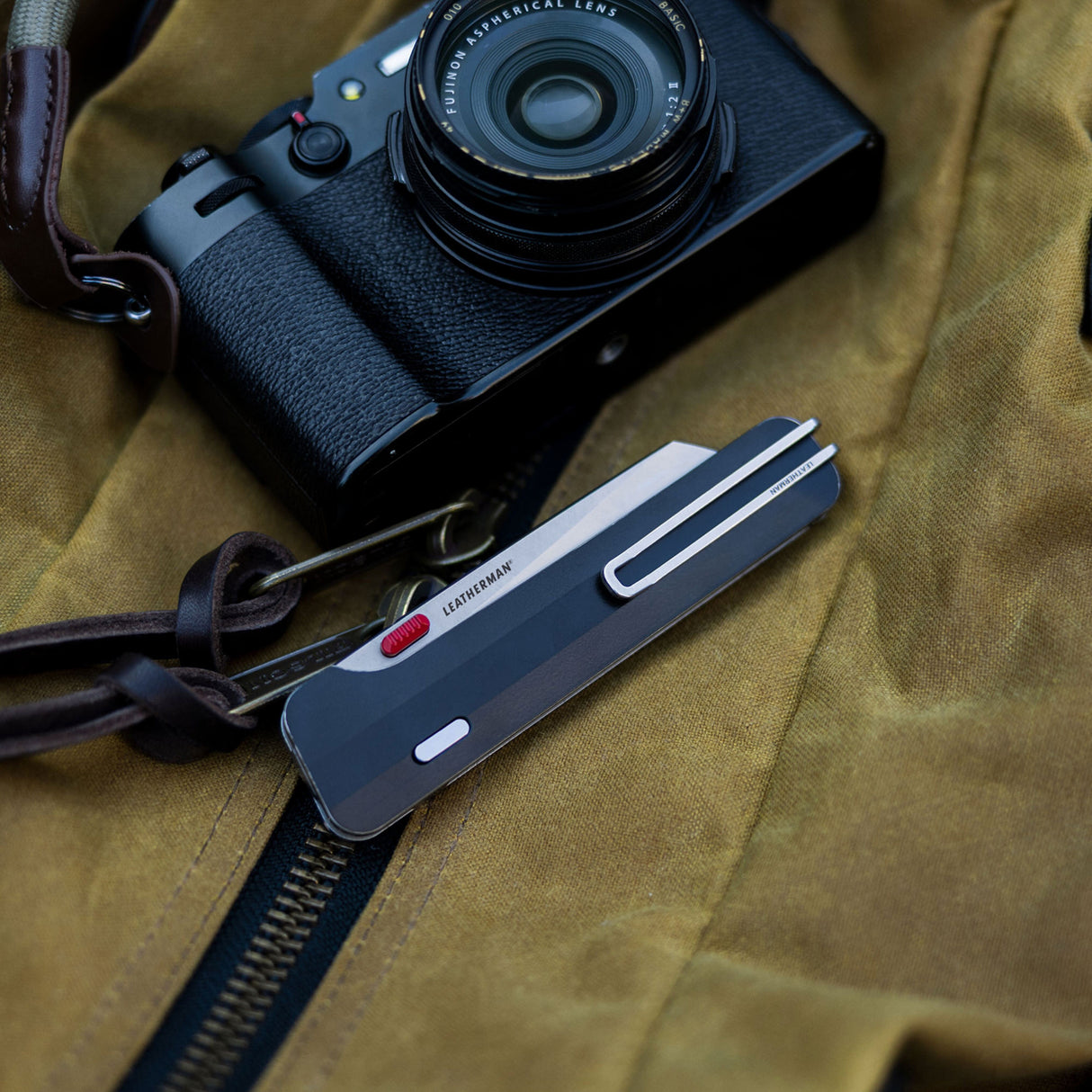 Translation missing: en.A sleek black camera positioned on a surface, next to closed Leatherman Glider