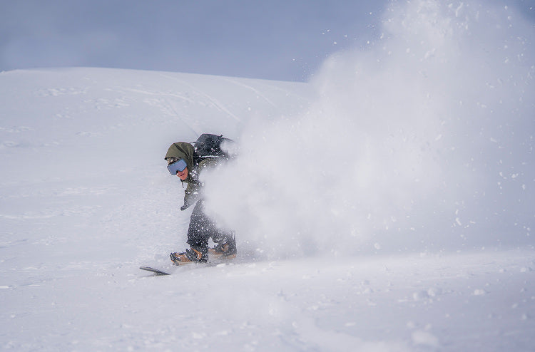 Translation missing: en.Snowboarder carving through fresh powder in a winter wonderland, showcasing dynamic movement and winter sport excitement