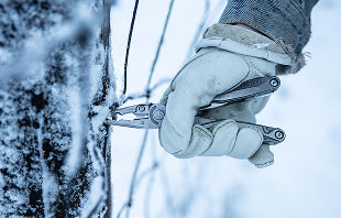 Translation missing: en.A person in gloves holds a pair Leatherman Charge+ TTi, preparing to cut something with focused attention