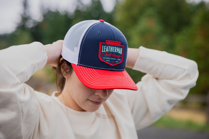 Translation missing: en.Person wearing a navy and red Leatherman Pacific Northwest Trucker hat with a visible brand logo