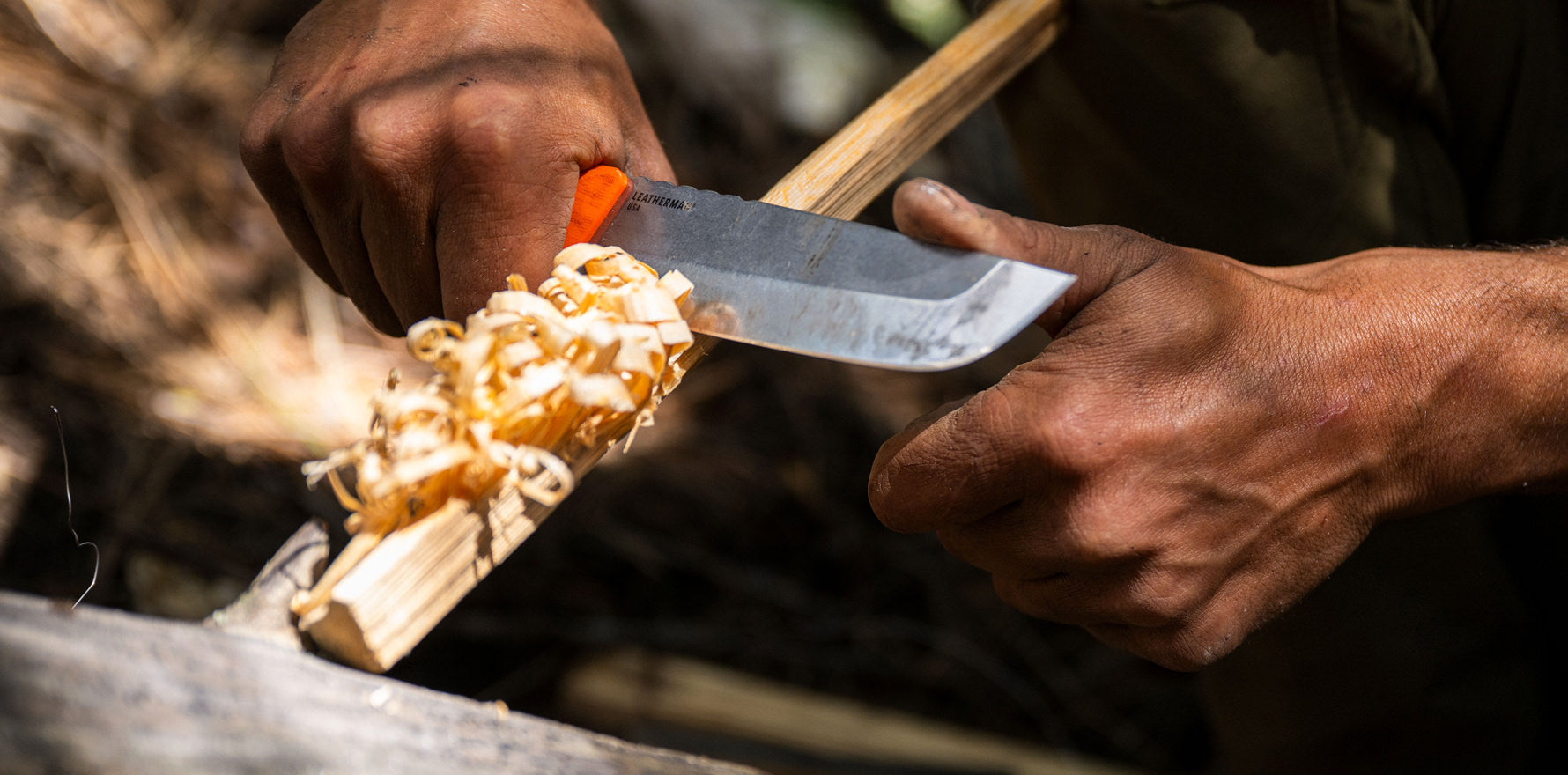 A man is using a Leatherman Pioneer to cut wood, demonstrating craftsmanship in a serene outdoor environment.