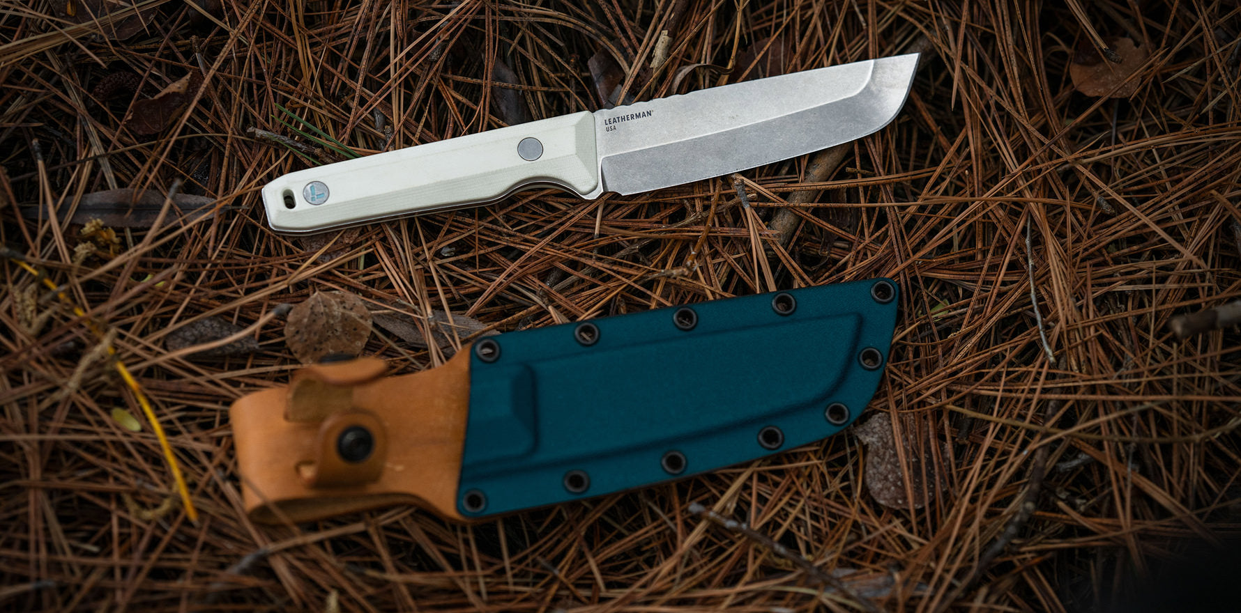 Leatherman Pioneer and sheath resting on a bed of pine needles in a natural setting.