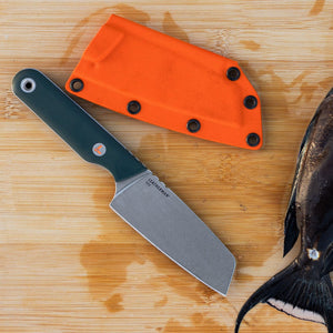 Translation missing: ko.Leatherman Rustle Evergreen knife with a green handle and stainless steel blade resting on a wooden cutting board next to its bright orange sheath and a partially cleaned fish