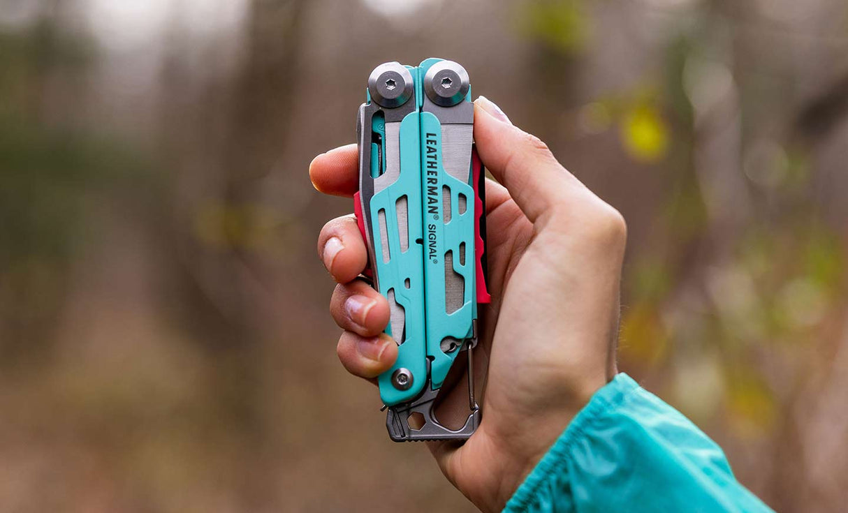 Translation missing: en.Person holding an aqua and stainless Leatherman Signal® multi-tool in a natural outdoor setting