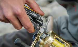 Translation missing: en.Person using a black and stainless Leatherman Signal® multitool to tighten a fishing reel