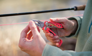 Translation missing: en.Person using a Guava Leatherman Skeletool® CX multitool pliers on a fishing line