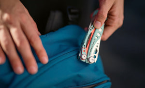 Translation missing: en.Hand holding a Paradise Leatherman Skeletool® CX multi-tool on top of a blue bag