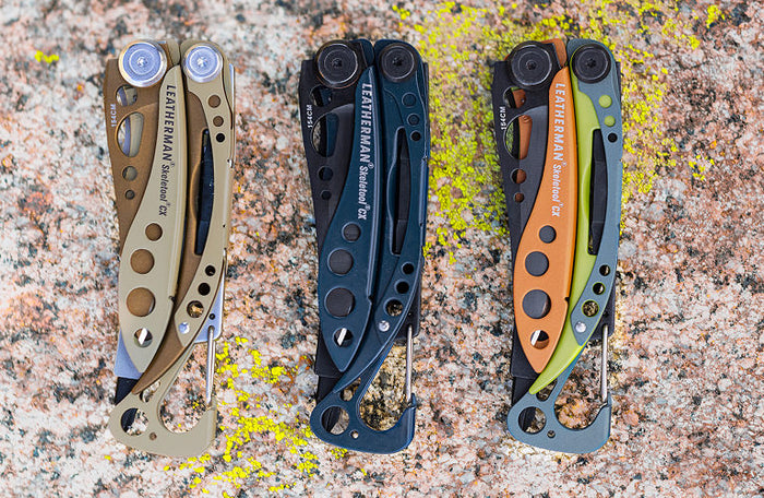 Translation missing: en.Three Leatherman Skeletool® Cx in sandstorm, nocturnal, and aurora colors against a textured rock background